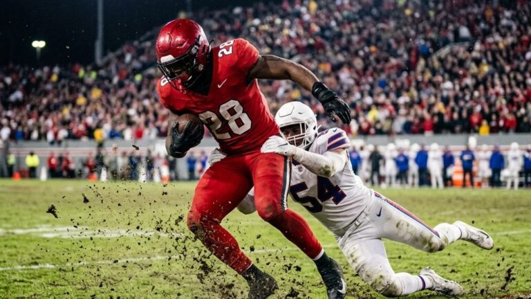 An anonymous professional football player running with the ball on the turf, illustrating the concept of DVOA football stats
